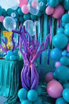 balloons and streamers are hanging from the ceiling in front of an understated table