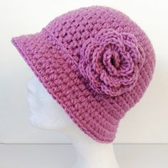 a crocheted hat with a flower on the top is shown in front of a mannequin head