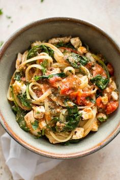 a bowl filled with pasta and vegetables on top of a table