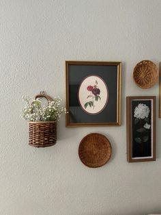 a wall with pictures and flowers on it, hanging on the wall next to a basket