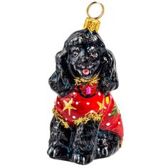 a glass ornament with a black dog wearing a red sweater and gold stars