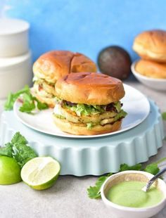 two sandwiches are on a plate next to some limes and other foodstuffs