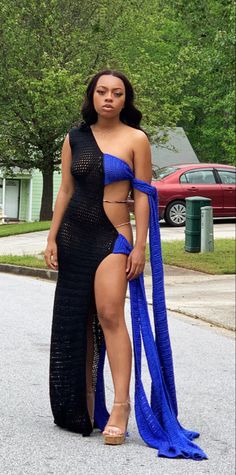 a woman in a black and blue dress standing on the street