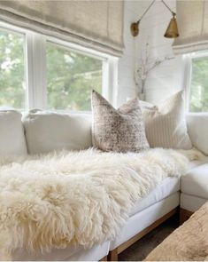 a white couch sitting next to a window in a living room with pillows on top of it