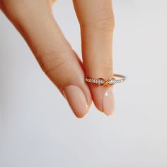 a woman's hand holding a diamond ring on top of her finger with the other hand