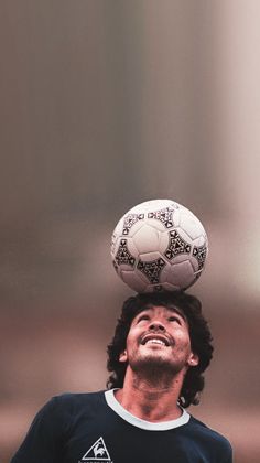 a man balancing a soccer ball on his head