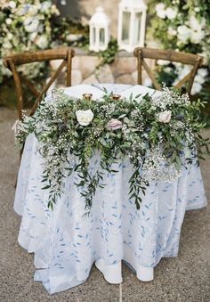 a table with flowers and greenery is set up for an outdoor wedding reception in the garden