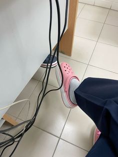 a pair of pink shoes are plugged in to a white wall with wires running through it