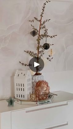 a white dresser topped with a vase filled with flowers and balls on top of it