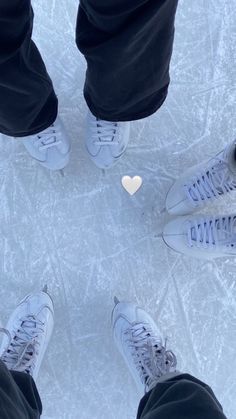 two people standing in the middle of an ice rink with their feet on the ground