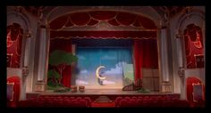 an empty stage with red curtains and a white moon hanging from the ceiling in front of it