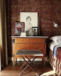 a bed room with a neatly made bed next to a dresser and pictures on the wall