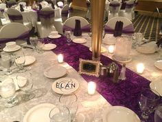 the table is set with white and purple linens, silverware, and candles