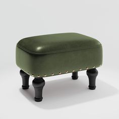 a green ottoman with black legs and studs on the top, sitting in front of a white background