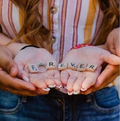 two people holding their hands with the word forever spelled in scrabble letters on them