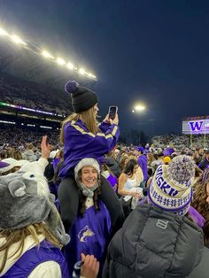 a group of people standing on top of a field at a football game wearing purple and gold outfits