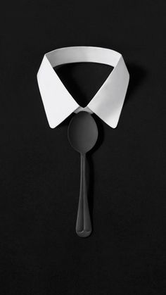 a spoon and some white paper on a black tablecloth with a shadow from it