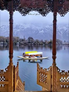 a boat floating on top of a lake next to a wooden structure with carved pillars