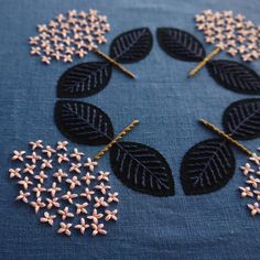 some black and white flowers are on a blue table cloth with gold pins in the middle