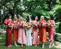 a group of women standing next to each other holding bouquets in front of trees