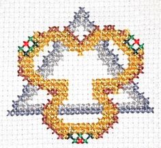 a cross stitched design with gold, silver and red beads in the shape of a heart