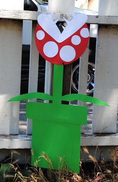 a paper flower is placed in front of a white picket fence with a heart on it