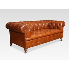 a brown leather couch with wooden legs and buttons on the armrests, sitting in front of a white background