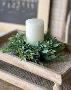 a white candle sitting on top of a wooden tray