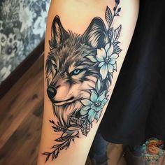 a woman's leg with a wolf and flowers tattoo on her thigh, which is decorated