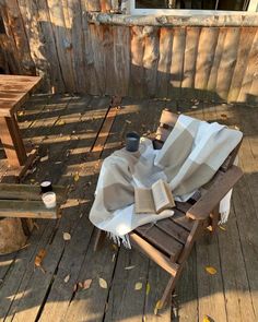 an empty chair on a wooden deck with a blanket draped over it and a cup