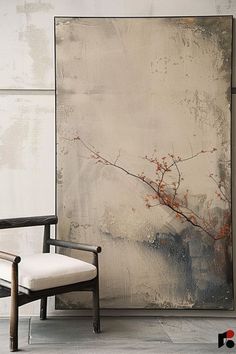 a chair sitting in front of a large painting on the side of a white wall