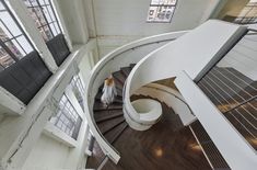 an aerial view of a spiral staircase in a building with lots of windows and wood flooring