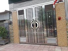 an entrance to a building with metal doors and decorative designs on the outside wall, surrounded by brick pavers