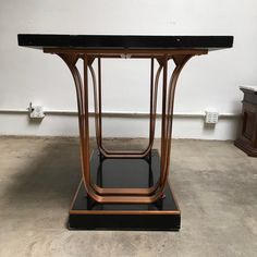 an art deco table with black marble top and metal base, on display in a room