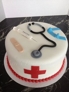 a white cake with red and blue icing on it's side, topped with a stethoscope