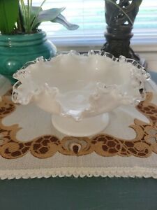 a white bowl sitting on top of a table next to a vase filled with flowers