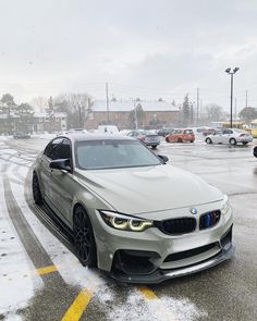 a silver car parked in a parking lot next to other cars on a snowy day