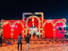 people standing in front of a red stage set up for a wedding ceremony at night