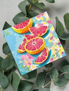 a piece of paper with cut up grapefruits on it next to green leaves