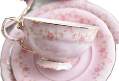 a pink tea cup and saucer sitting on top of each other with gold trimmings