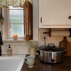 a kitchen counter with a large pot on top of it next to a sink and window