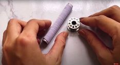 two hands are working on an object that looks like a bead with holes in it