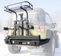 a yellow truck with a rack attached to it's rear bumper in the snow