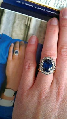 a woman's hand with a ring on it and a magazine in the background