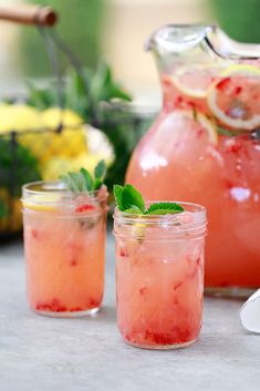 two jars filled with watermelon and mint sitting on a table next to lemons