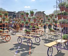 several wooden tables and benches with plants on them in the middle of a parking lot