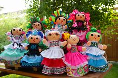 a group of dolls sitting on top of a wooden table