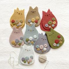 a group of cat shaped brooches sitting on top of a white table next to a ball of thread