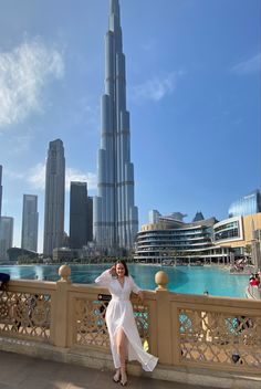 a woman standing on a bridge in front of the burj tower, dubai