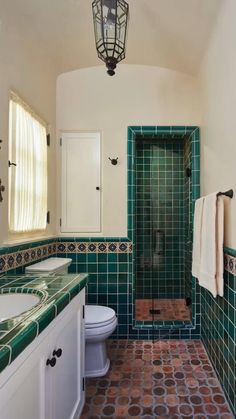 a bathroom with green and brown tiles on the walls